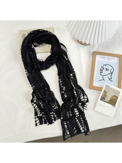 Black openwork scarf arranged at full length on a neutral tabletop