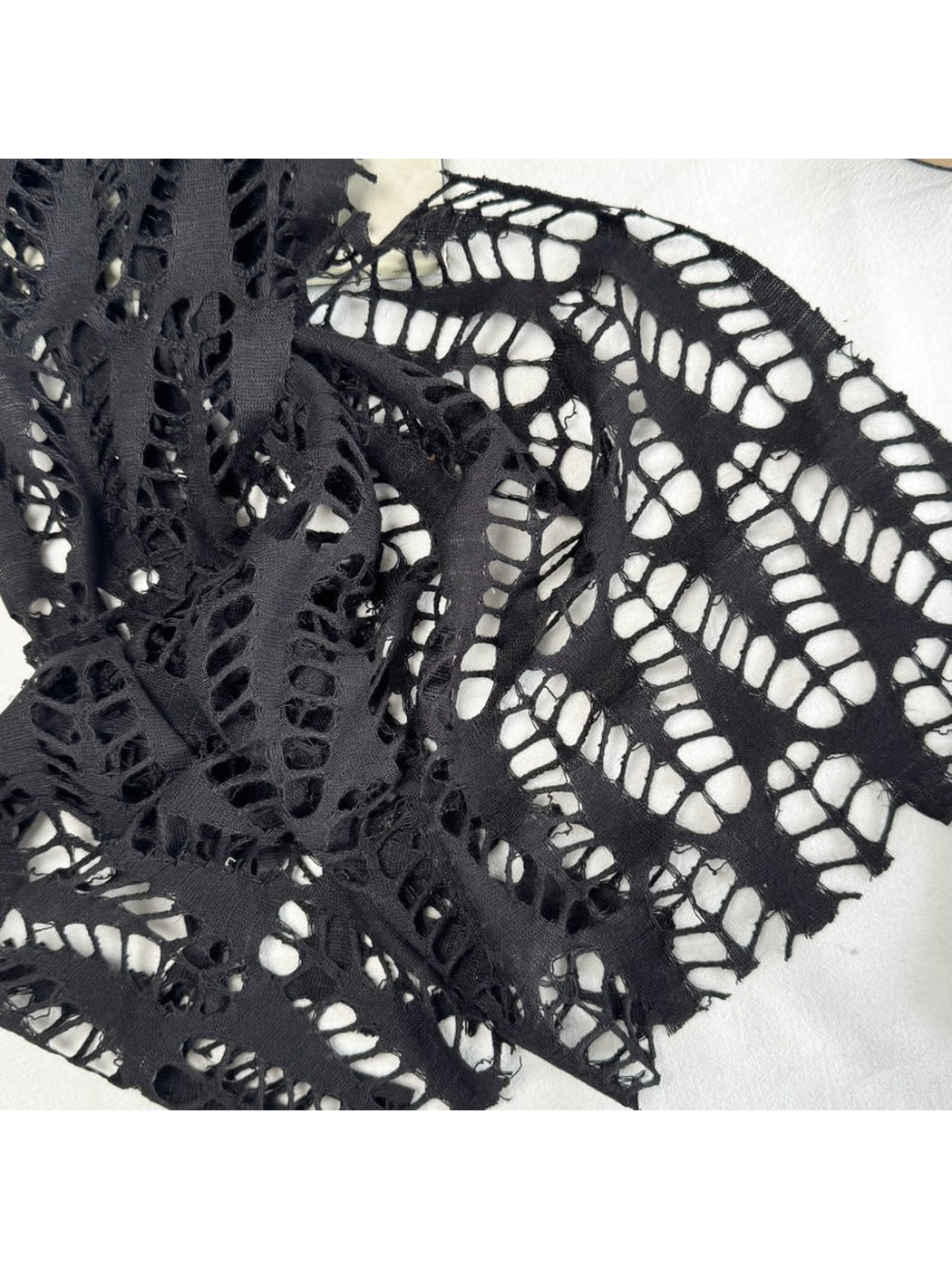 Close-up of the black scarf's irregular openwork stripe pattern