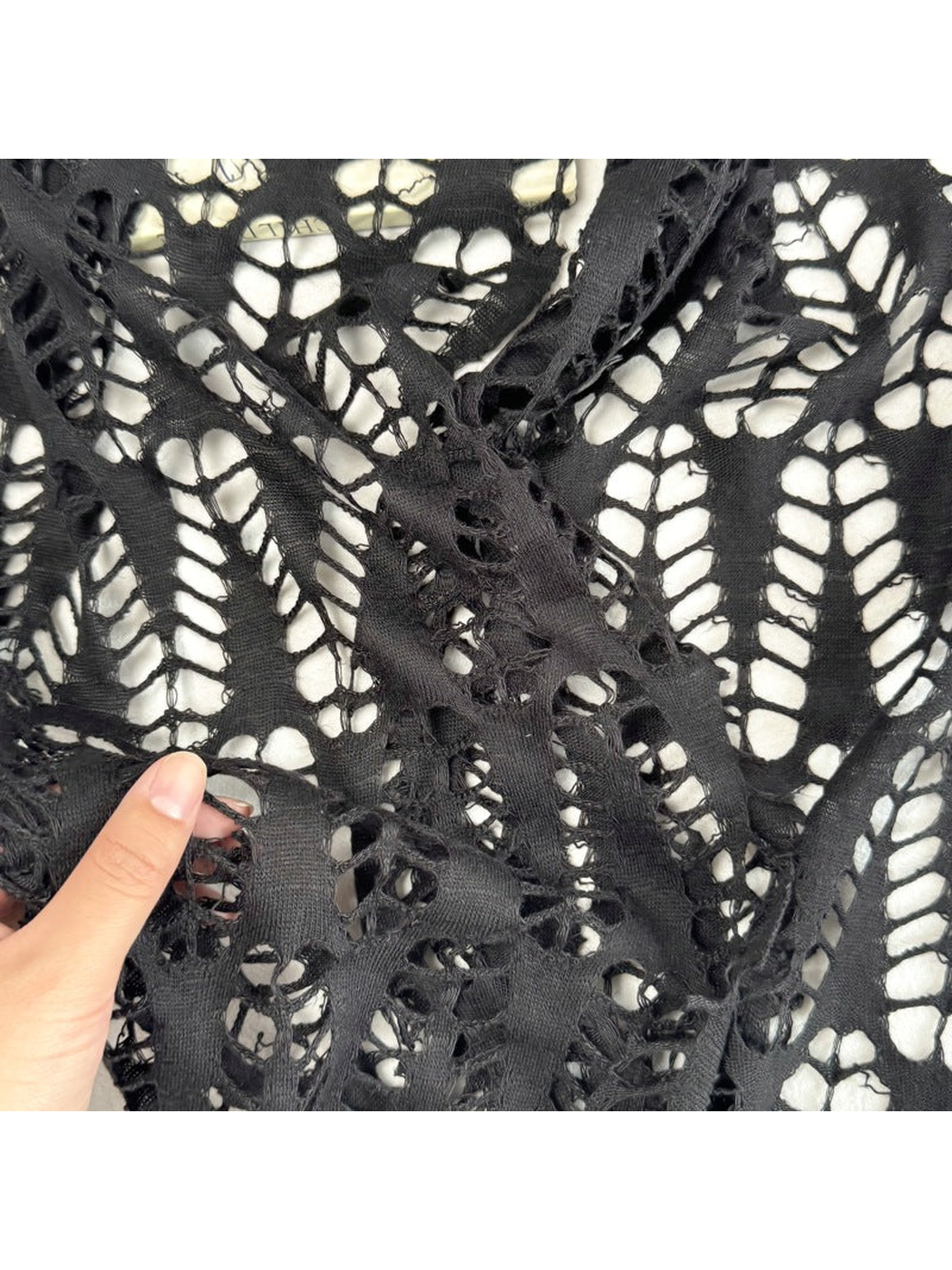 Close-up of large openwork cutouts and narrow bands on the black scarf