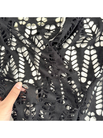 Close-up of large openwork cutouts and narrow bands on the black scarf