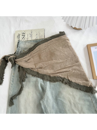 Beige Green triangle scarf tied over light-wash jeans
