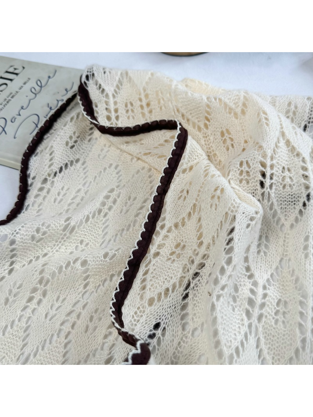 Close-up of cream openwork leaf pattern and dark brown scalloped trim