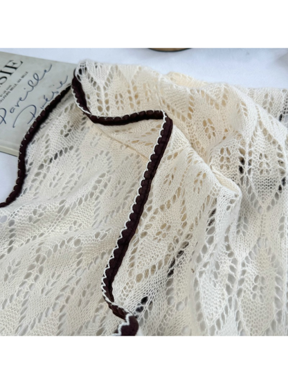 Close-up of cream openwork leaf pattern and dark brown scalloped trim