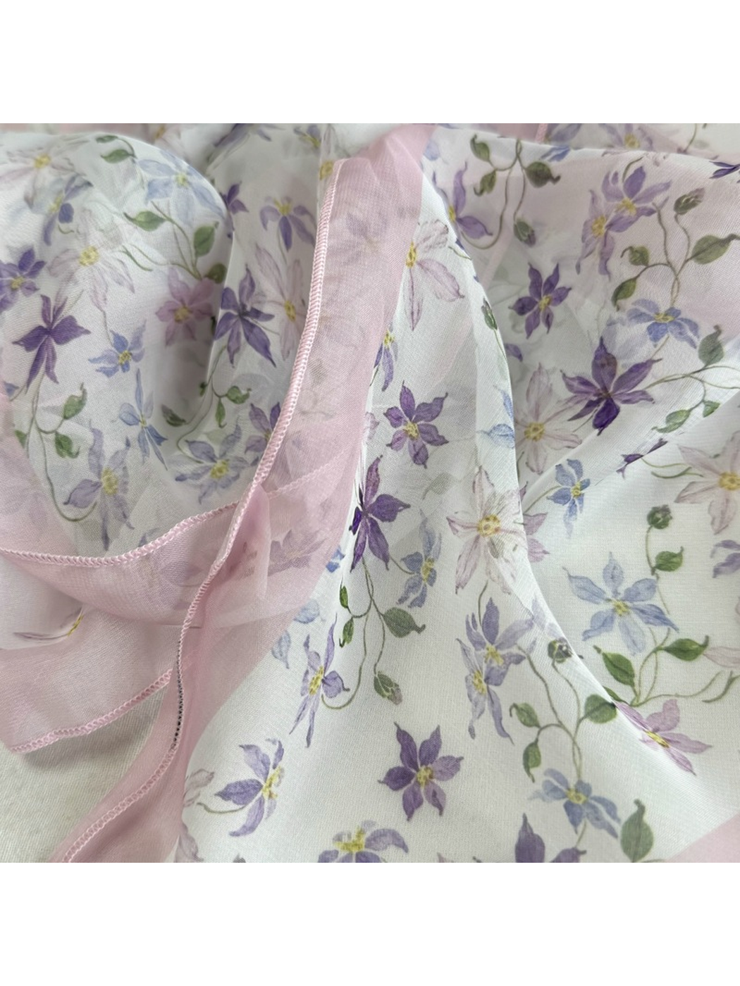 Close-up of purple floral print, translucent border, and stitched edge
