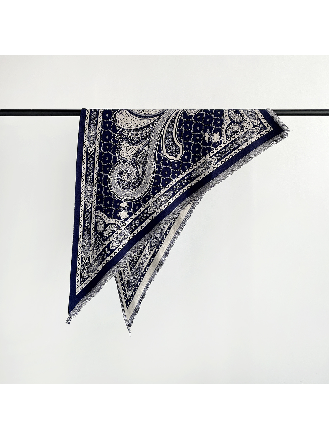 Navy paisley triangle scarf folded over a display rail