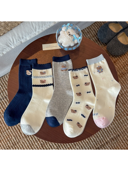 Five bear motif crew sock styles arranged together in navy, gray, and ivory