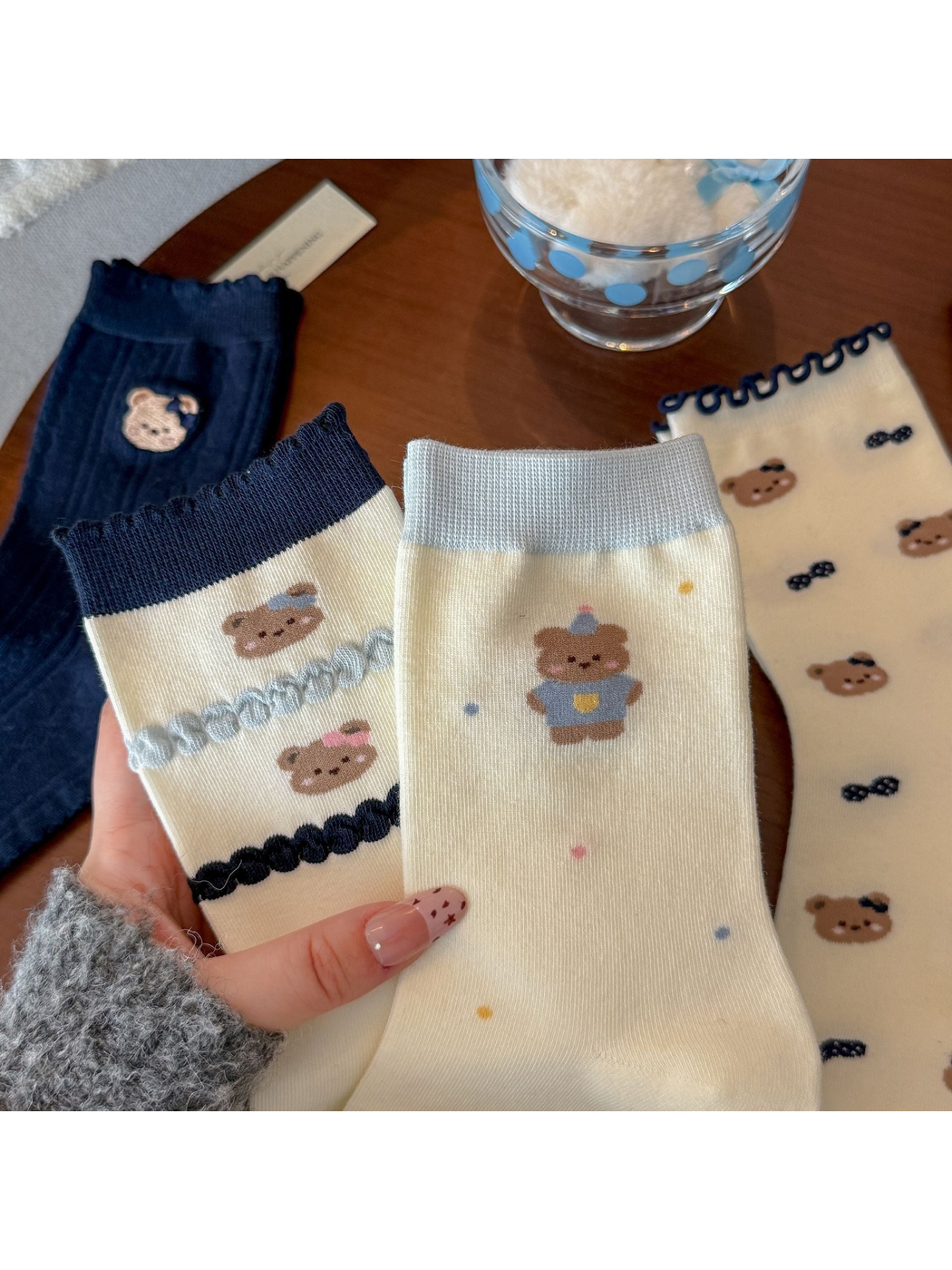 Close view of multiple bear motif sock styles in ivory, gray, and navy