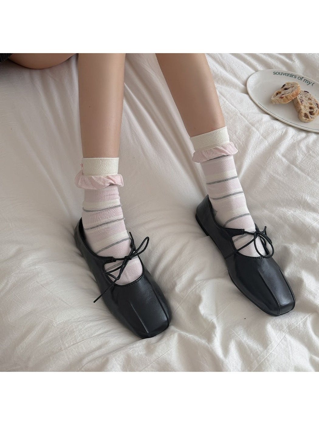 Pink striped crew socks with ruffled cuffs worn with black lace-up shoes