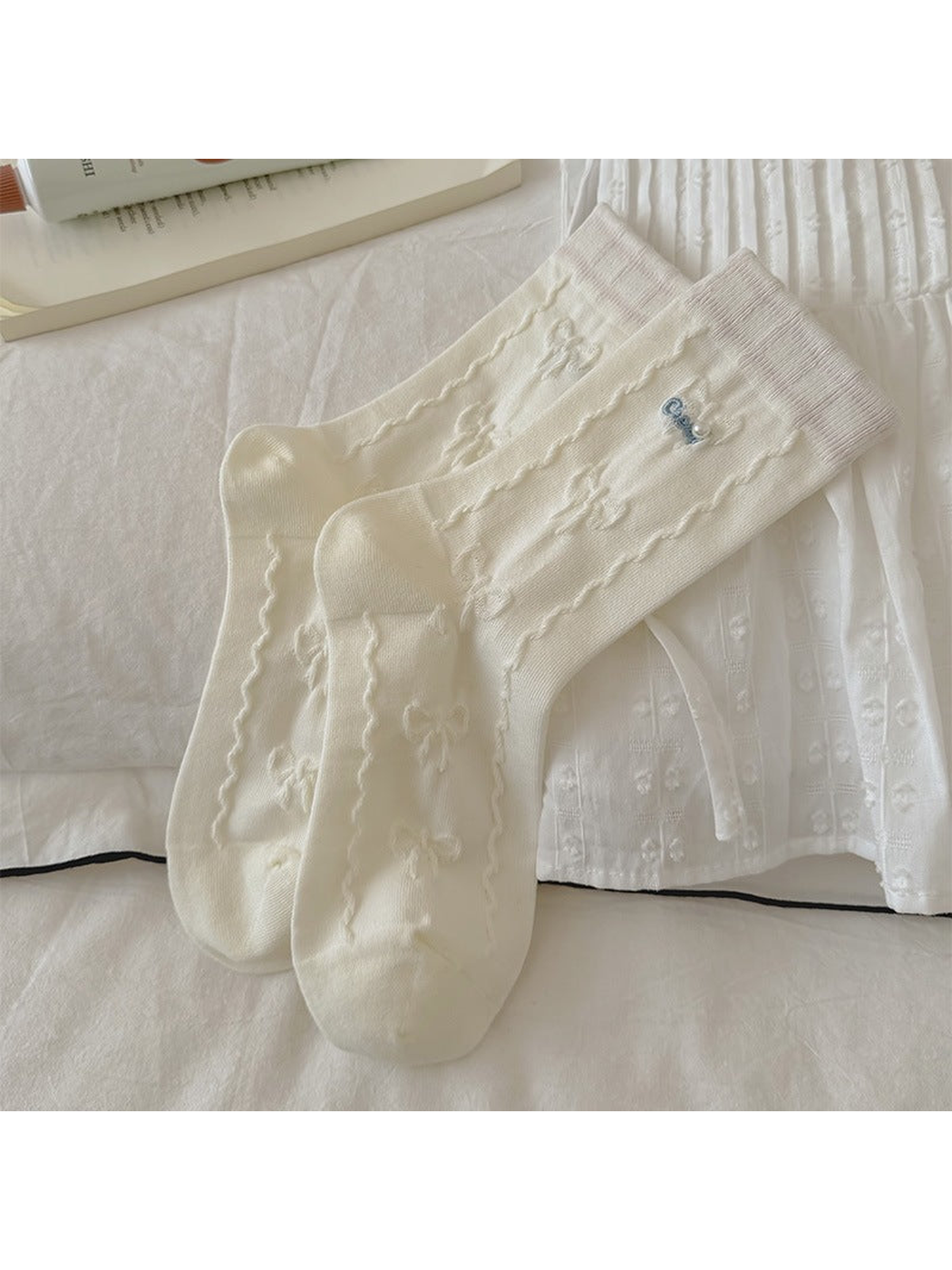 Ivory crew socks with bead-accented bows, laid flat