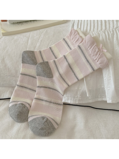 Pink striped crew socks with gray toes and ruffled cuffs, laid flat