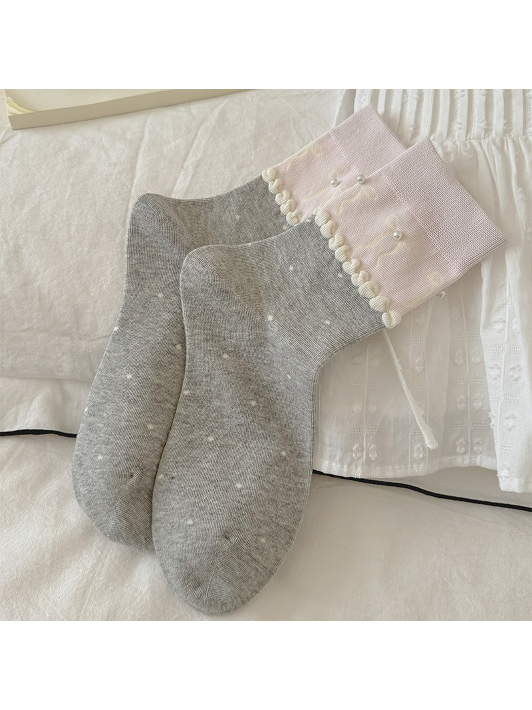 Gray polka-dot crew socks with pink embellished cuffs, laid flat