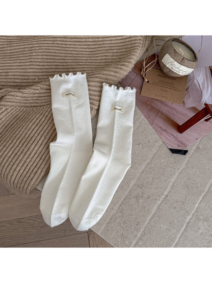 White crew socks with ruffle cuffs and small fabric labels