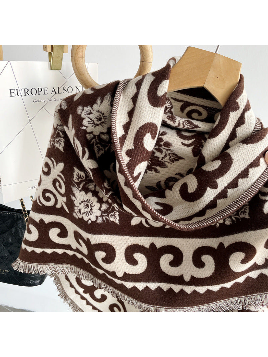 Close-up of the dark brown floral pattern, scrolling border and fringed edge