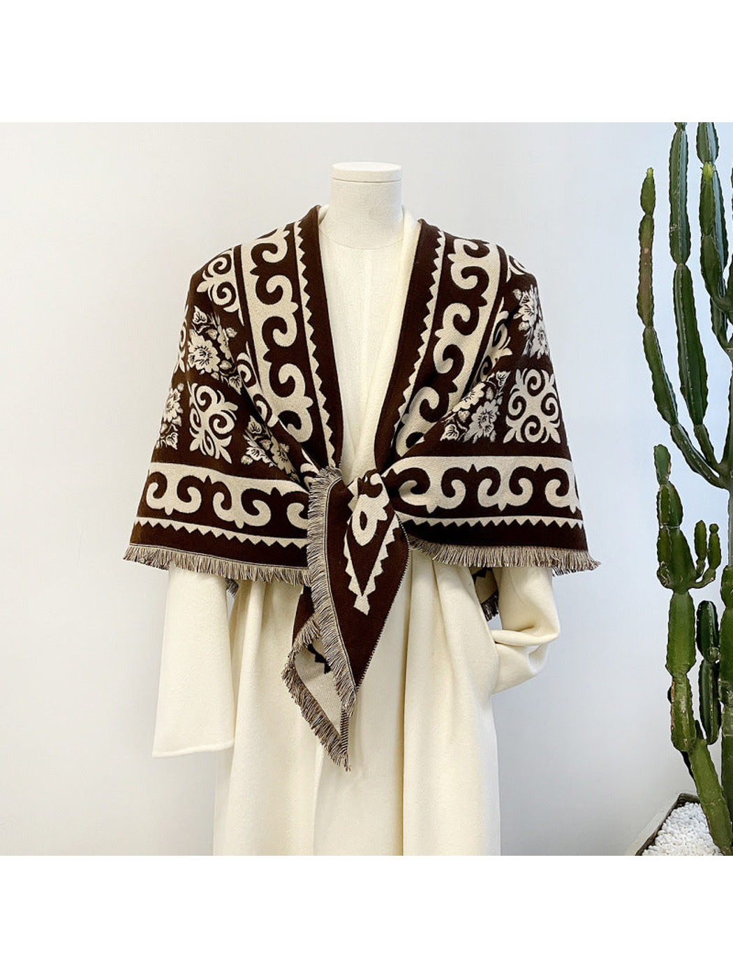 Dark brown patterned triangle scarf tied over a cream garment