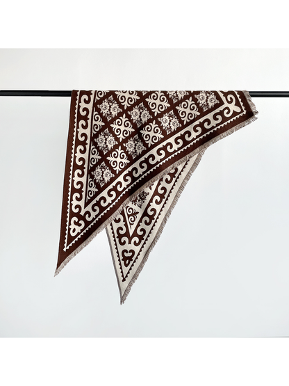 Dark brown patterned triangle scarf folded over a display rail
