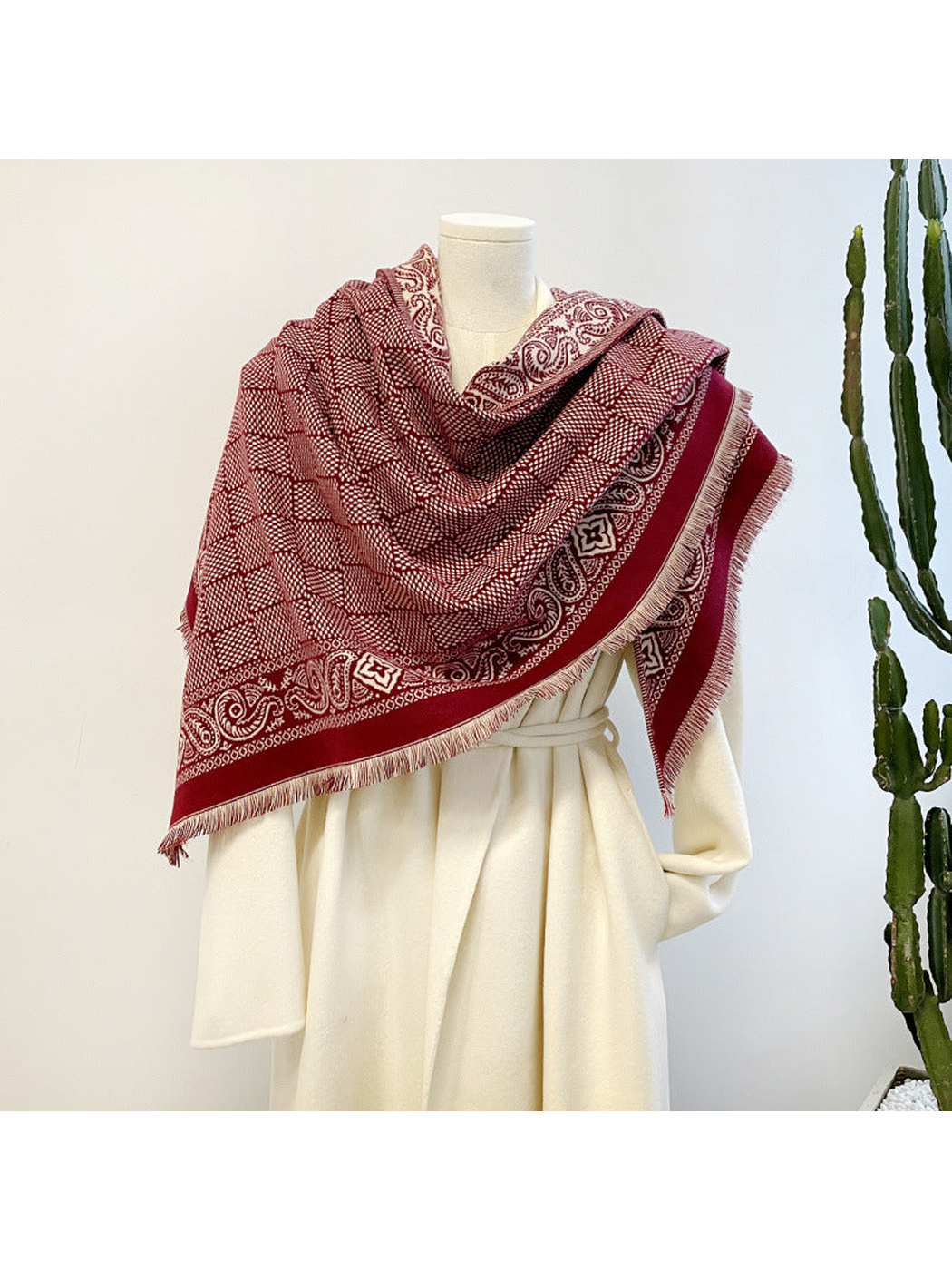Burgundy geometric scarf with paisley border and short fringe draped on a mannequin