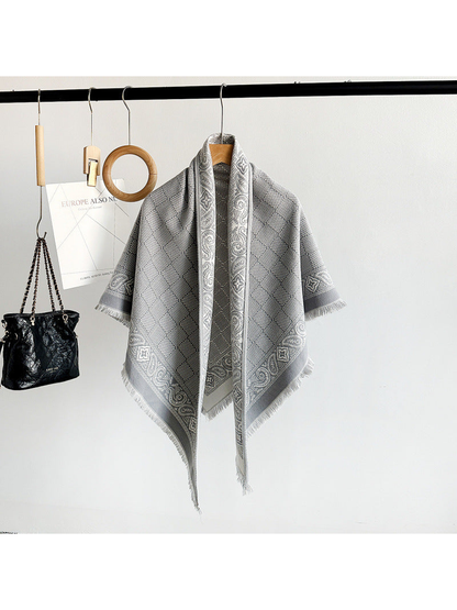 Gray geometric scarf with paisley border and short fringe displayed on a hanger
