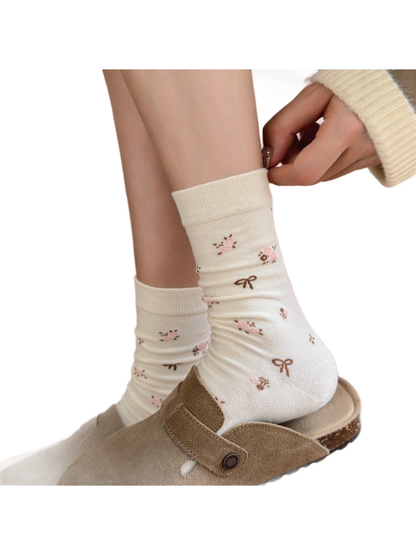 Ivory floral crew socks worn with taupe clogs, close view