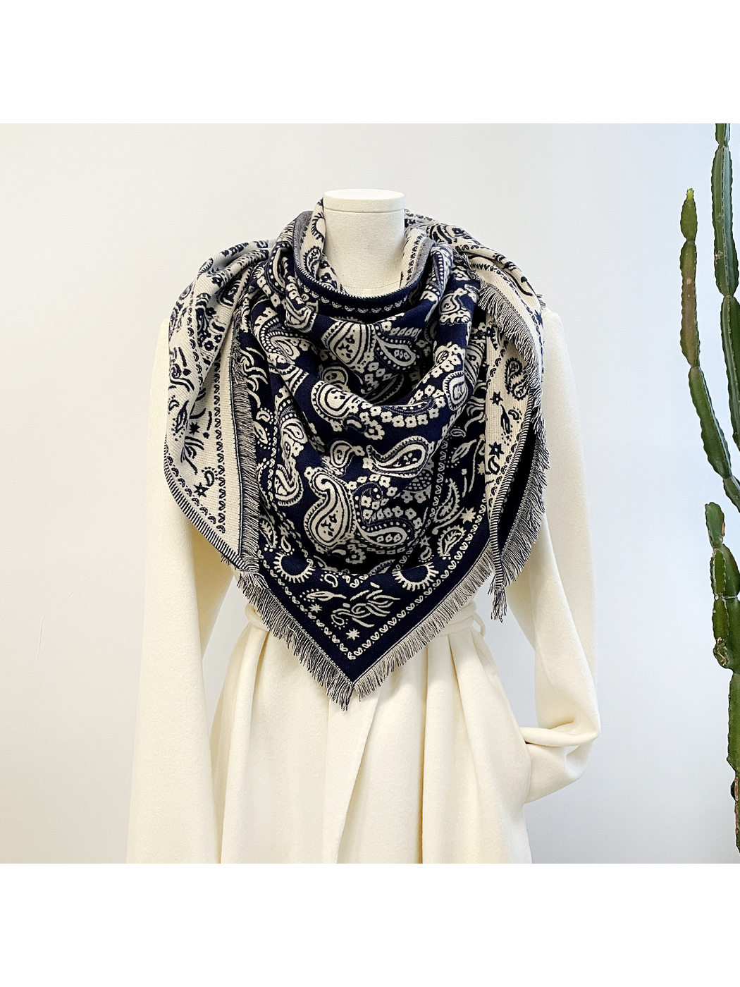 Navy paisley triangle scarf with short fringe draped on a mannequin