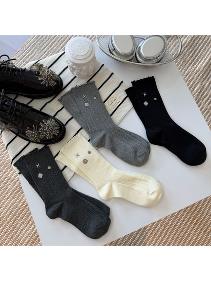Ivory, black, gray and dark gray crew socks with shaped heels, closed toes and silver-tone accents