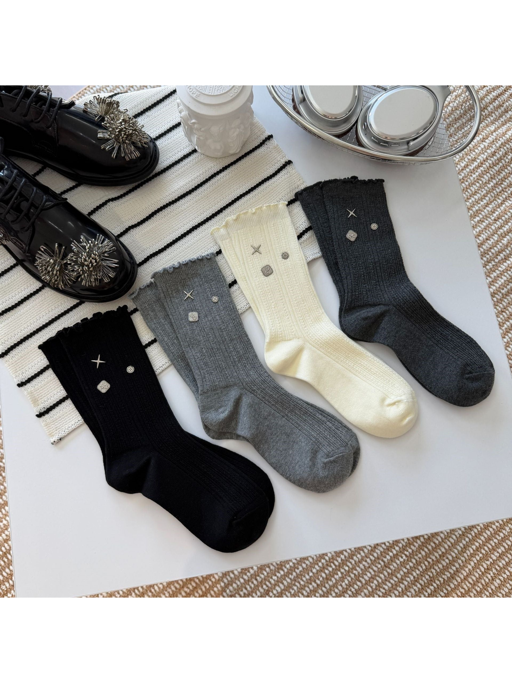 Ivory, black, gray and dark gray crew socks displayed with coordinating accessories