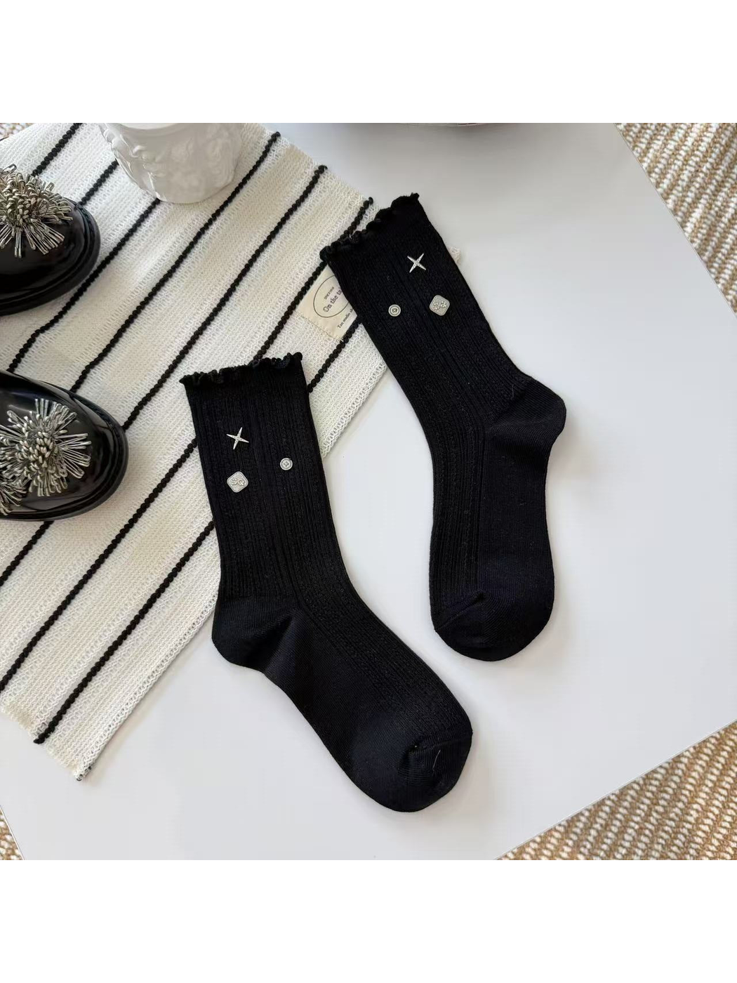 Black crew socks with ribbed texture, ruffled cuffs and silver-tone accents