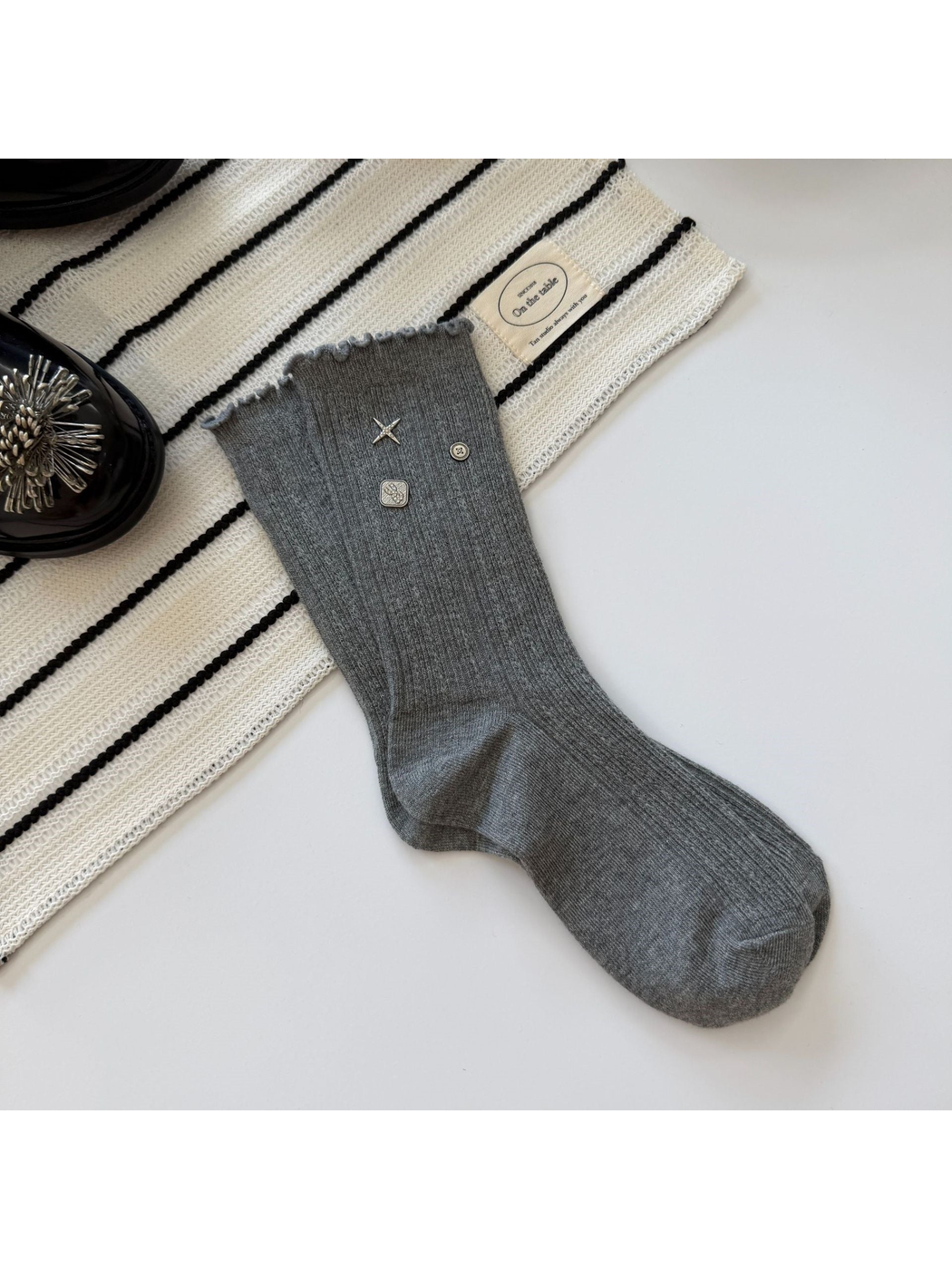 Gray crew sock with ribbed texture, ruffled cuff and silver-tone accents