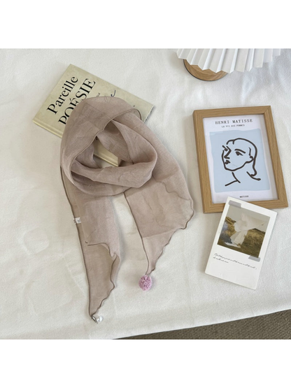 Greige sheer scarf with wavy edges and pom-pom and bead end accents