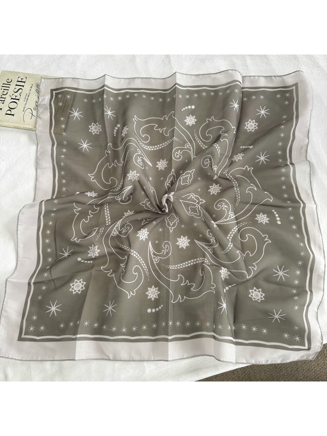 Greige square scarf with star and scroll motifs displayed open