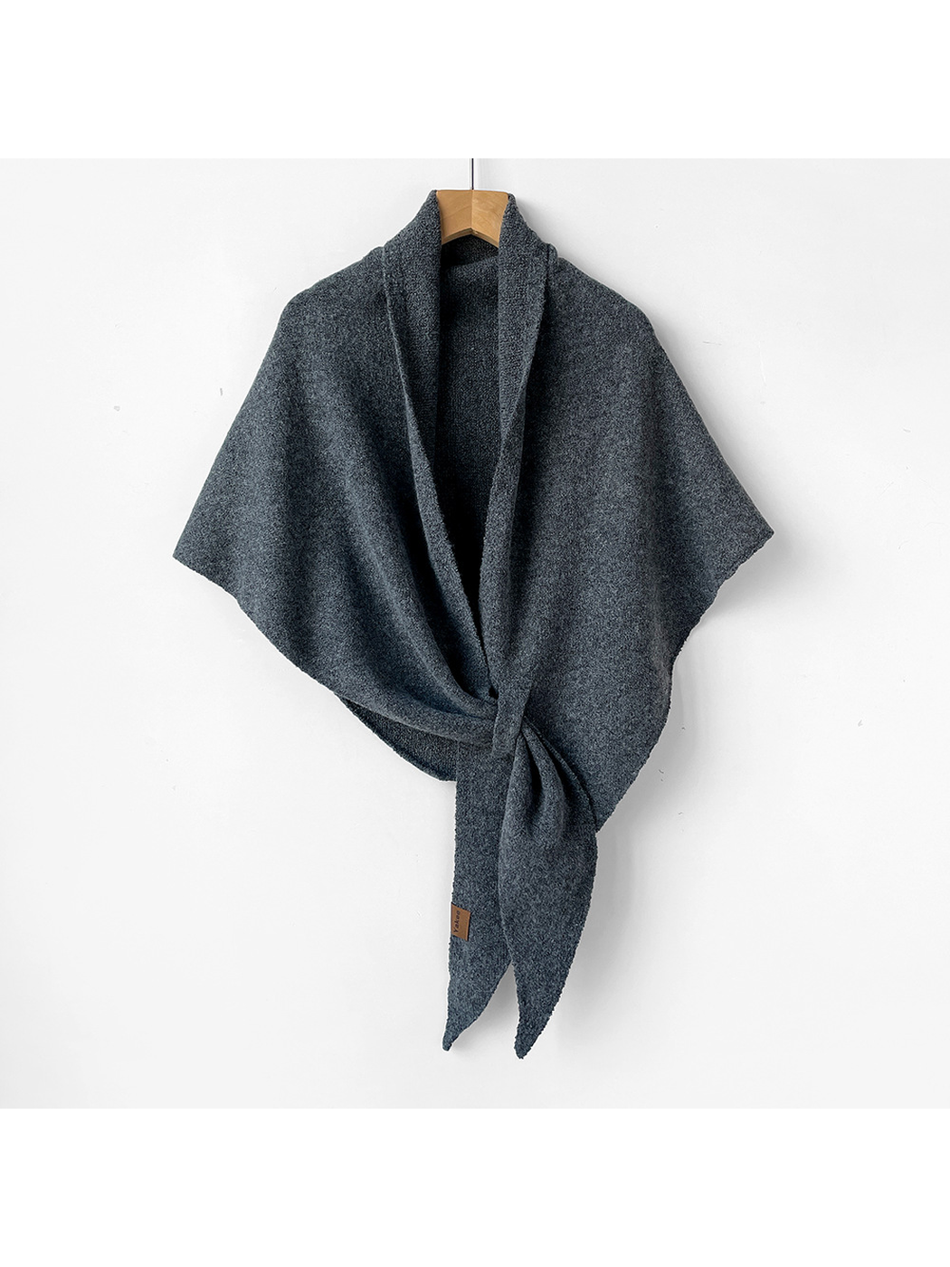 Dark gray triangle shawl tied on a wooden hanger