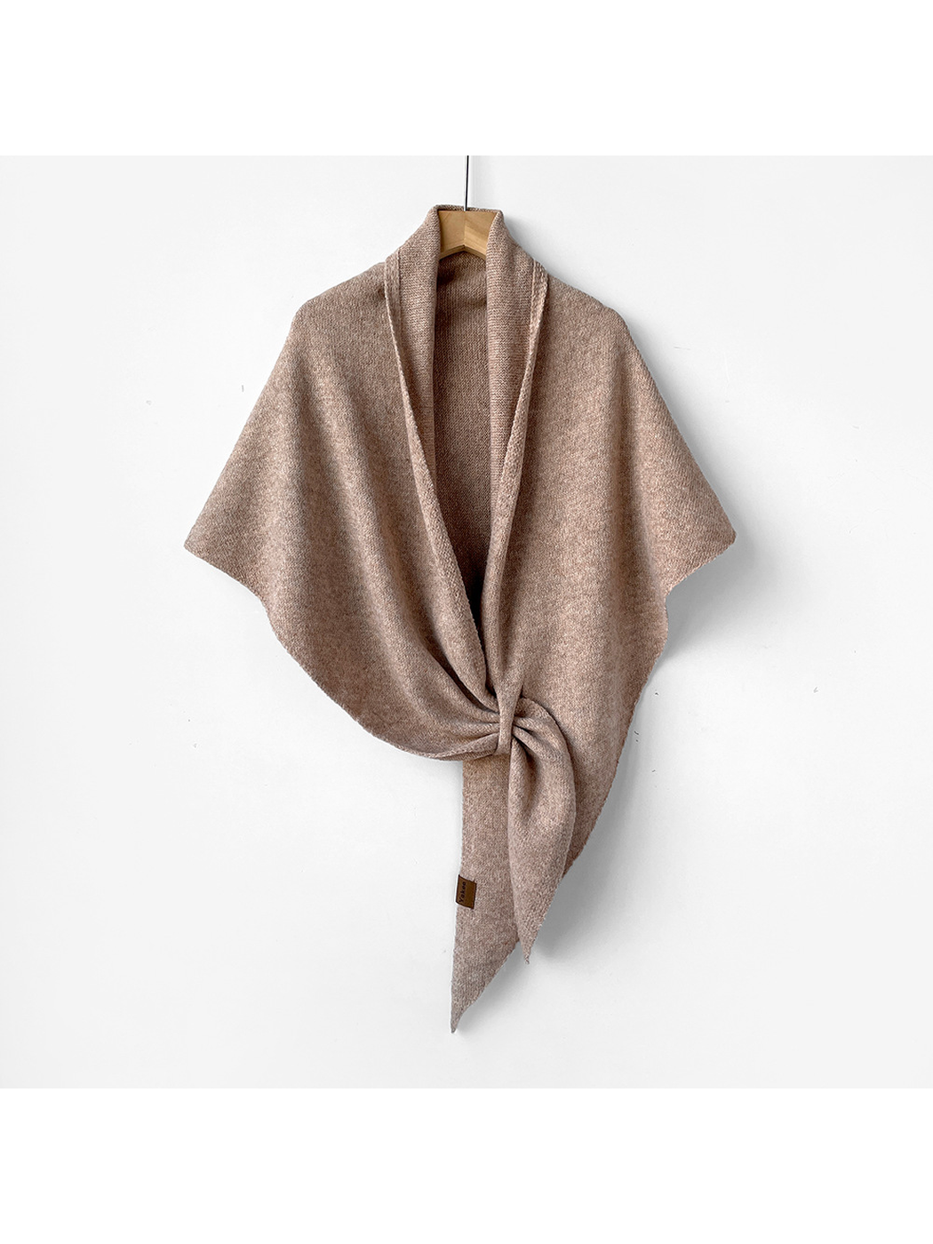 Light beige triangle shawl tied on a wooden hanger