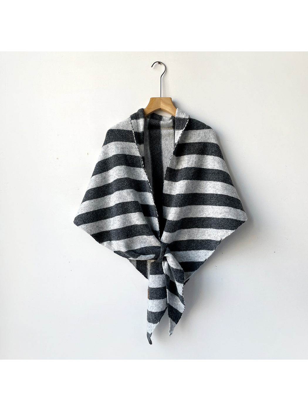 Gray and ivory striped triangle shawl tied on a wooden hanger