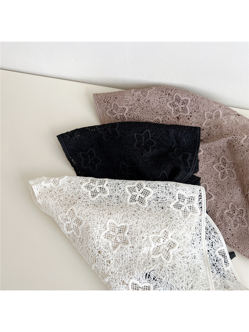 Close view of Ivory, Black and Light Coffee scarves with repeating floral openwork