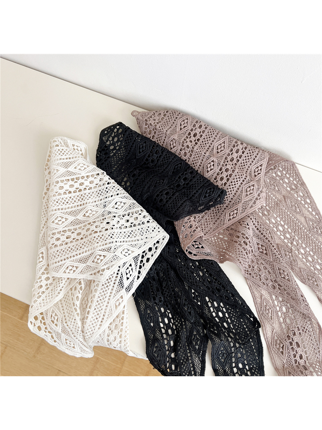 Ivory, Black and Light Coffee openwork triangle scarves arranged in overlapping folds
