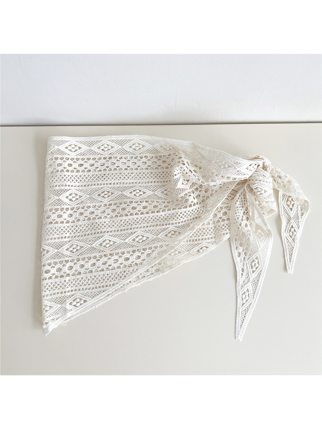 Ivory openwork triangle scarf folded to show its geometric lace pattern