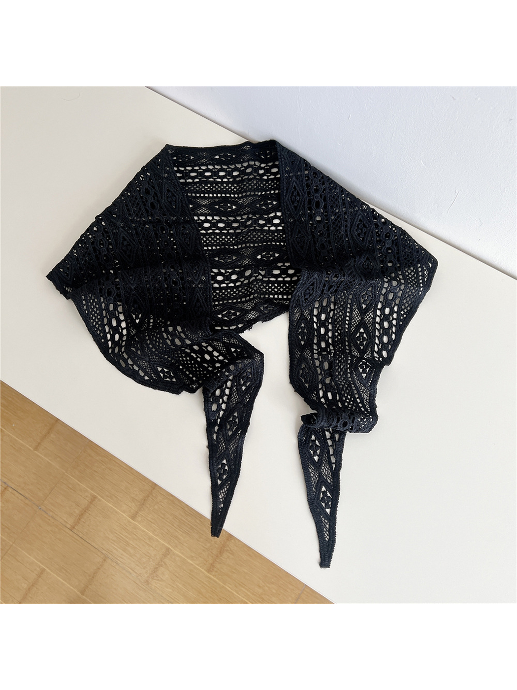 Black openwork triangle scarf laid open with pointed tie ends