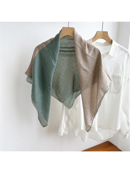 Two-tone green and blush floral scarf draped open on a hanger