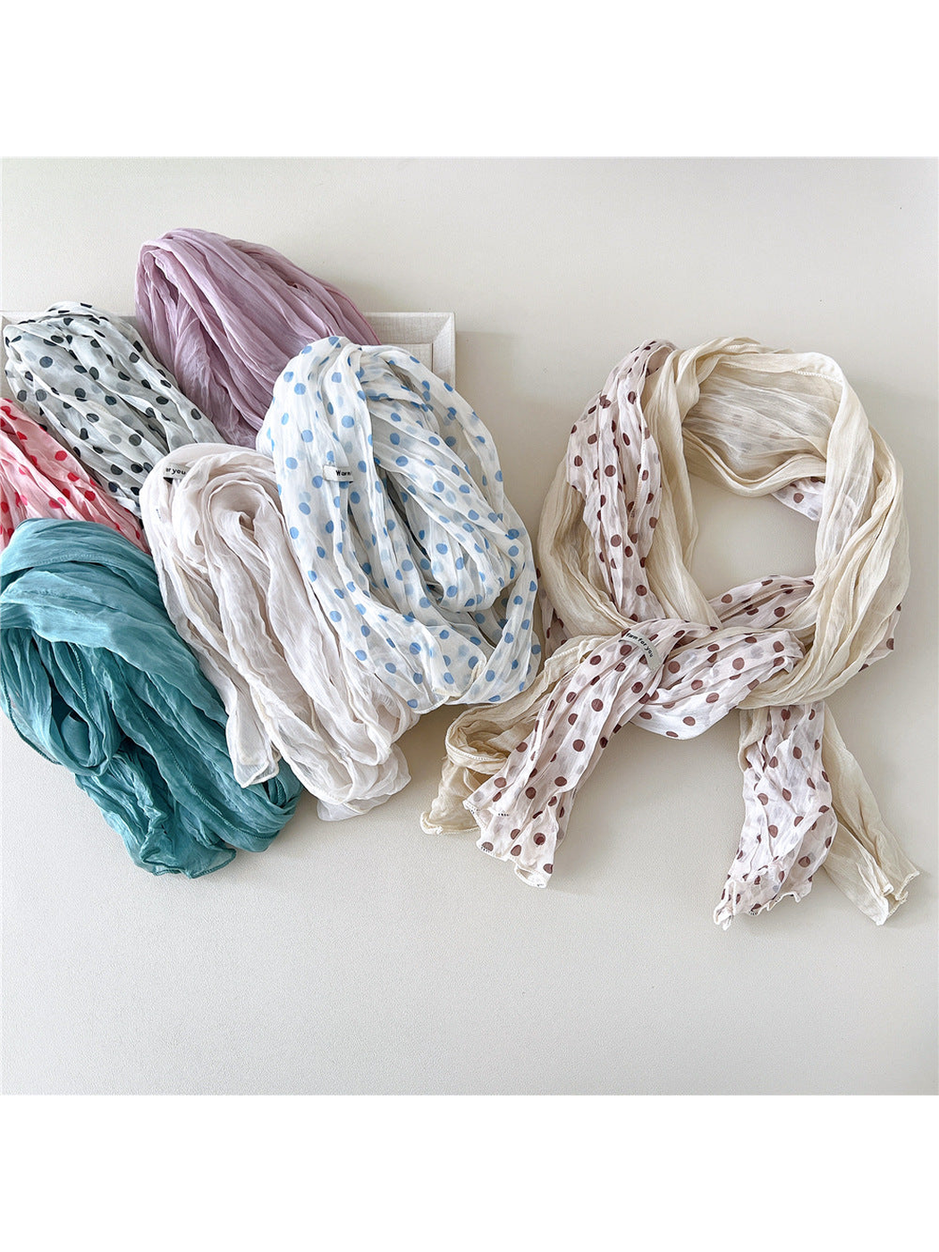 Solid and polka-dot crinkled scarves arranged together