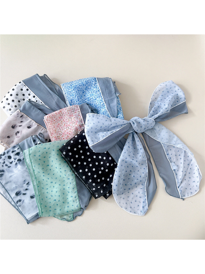 Multiple scarf styles arranged together with a light blue sprig scarf tied in a bow