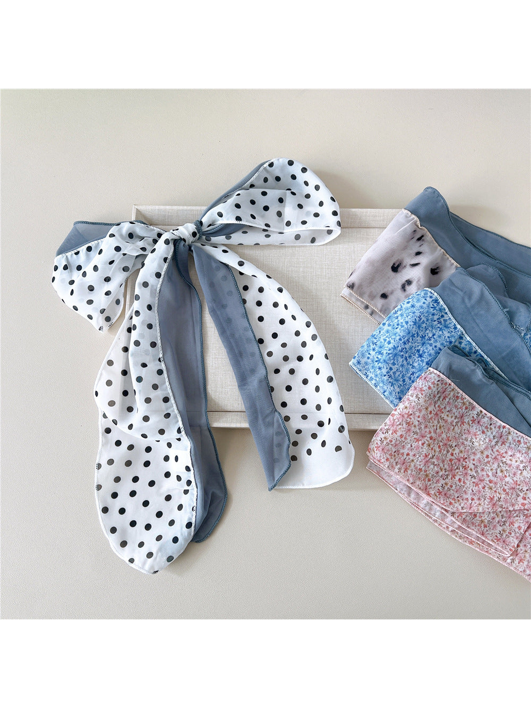 White dot scarf tied in a bow beside floral and animal-print styles