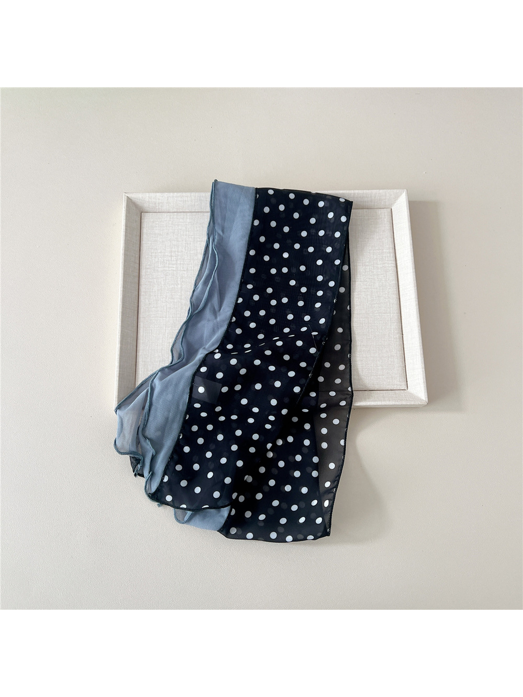 Folded black dot scarf showing the contrasting blue-gray panel and sheer patterned section