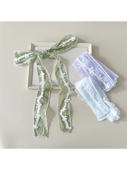 Green scarf tied in a bow beside folded Light Purple and Light Blue scarves