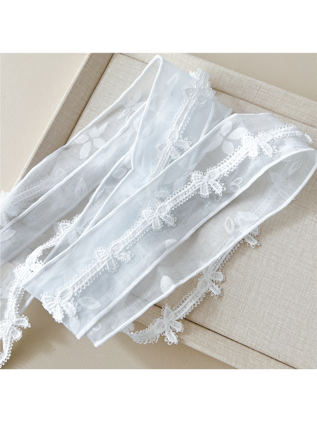 Close-up of sheer floral fabric, finished edges and butterfly lace trim