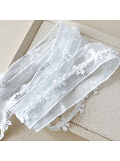 Close-up of sheer floral fabric, finished edges and butterfly lace trim