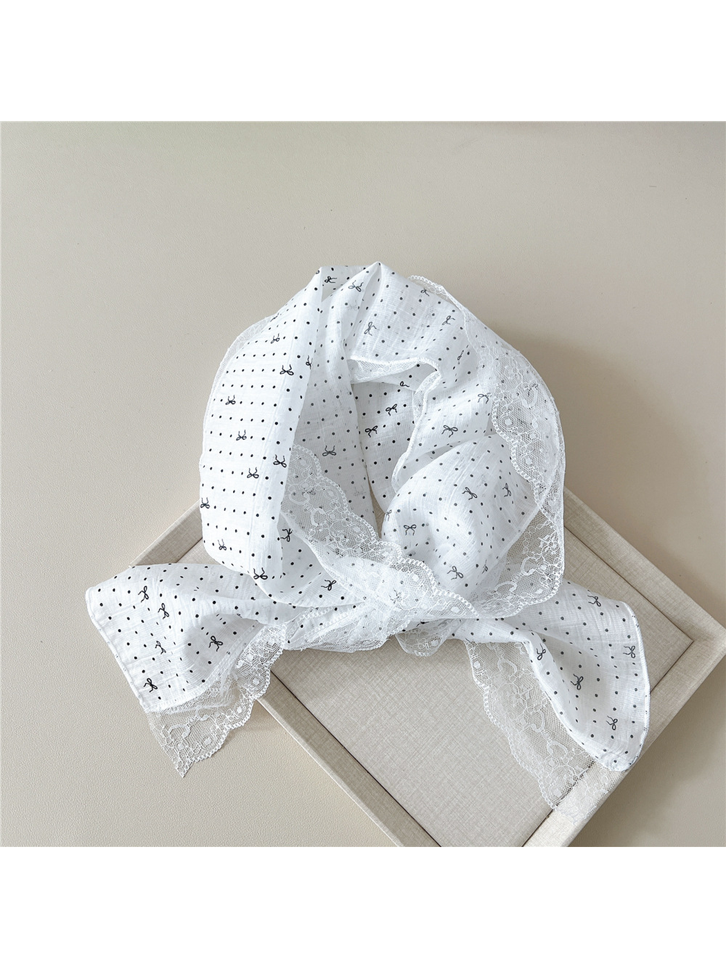 White dotted bow scarf draped over a neutral display tray