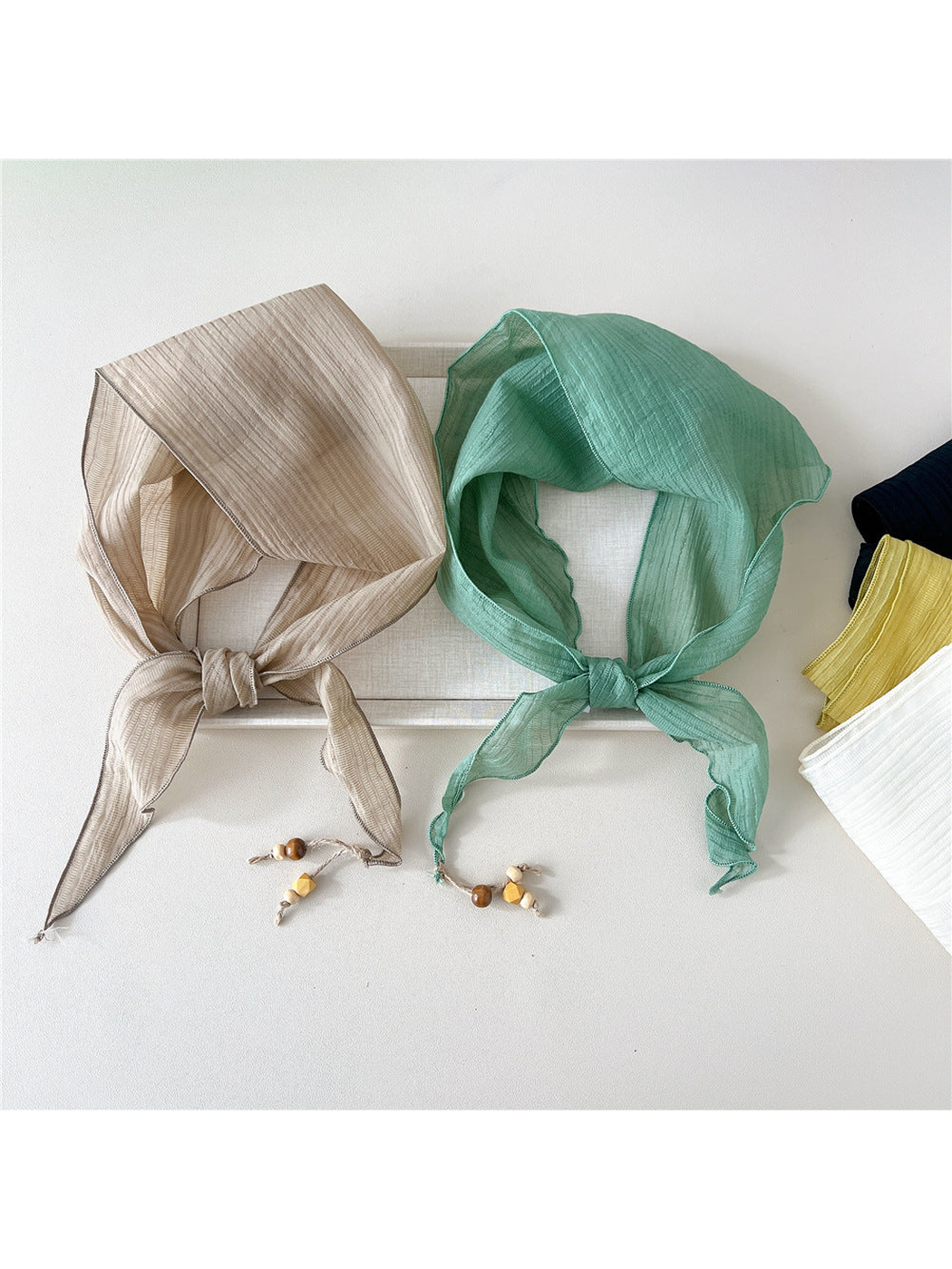 Beige and mint textured scarves tied beside folded color options