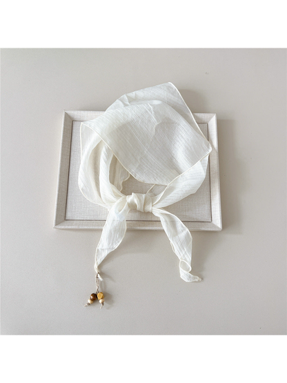 Ivory textured scarf tied with bead detail at one pointed end