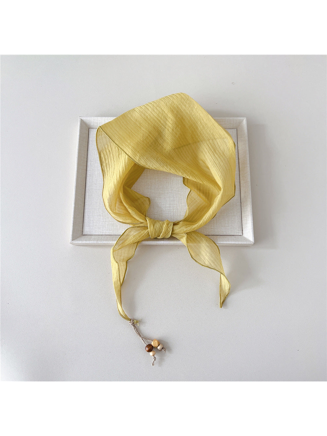 Yellow textured scarf tied with bead detail at one pointed end