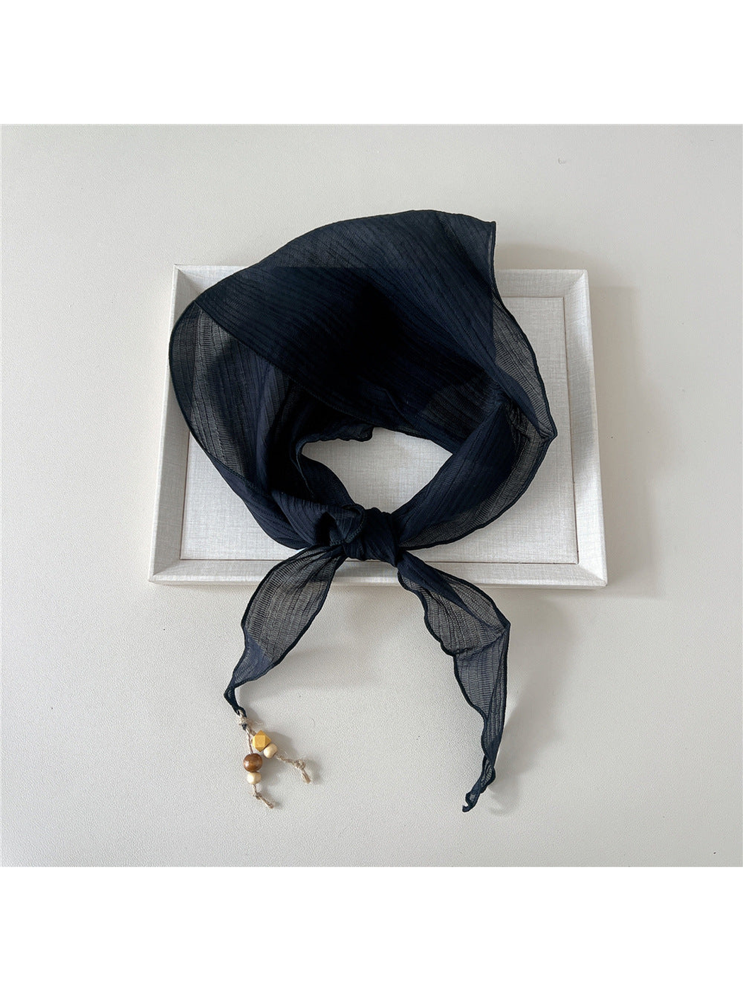 Navy textured scarf tied with bead detail at one pointed end