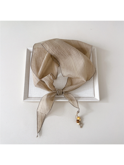 Beige textured scarf tied with bead detail at one pointed end